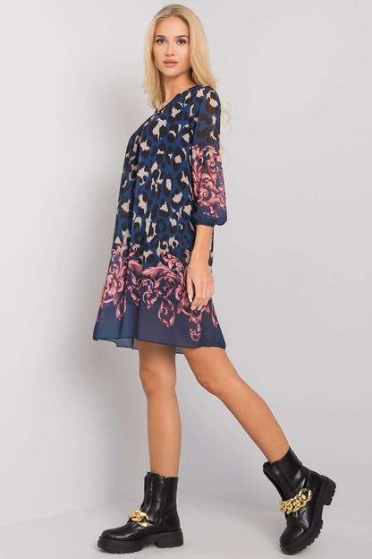 Luxurious Och Bella Loose-Fitting Daydress with 3/4 Sleeves and Rounded Neckline, beautifully drapes in navy blue, enhanced with striking pink floral accents and stylish black boots.