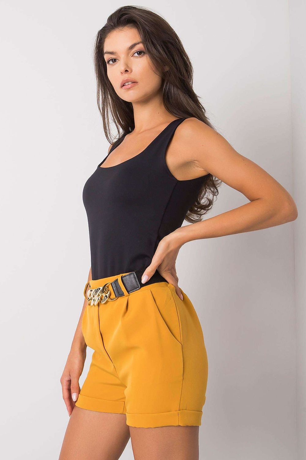 Side profile view of Luxury Women's Elastic Waistband Shorts with Slip Pockets and Decorative Belt by Italy Moda, model showcasing a fashionable ensemble with mustard shorts.