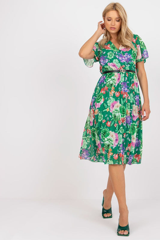 Elegant flared floral summer dress with belt and pleated hem by Italy Moda, model showcasing vibrant green fabric with colourful floral patterns.