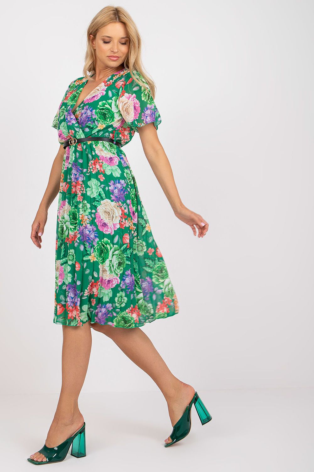 Chic floral summer dress with belt and pleated hem by Italy Moda, model posing in a beautiful green design featuring rich floral prints.