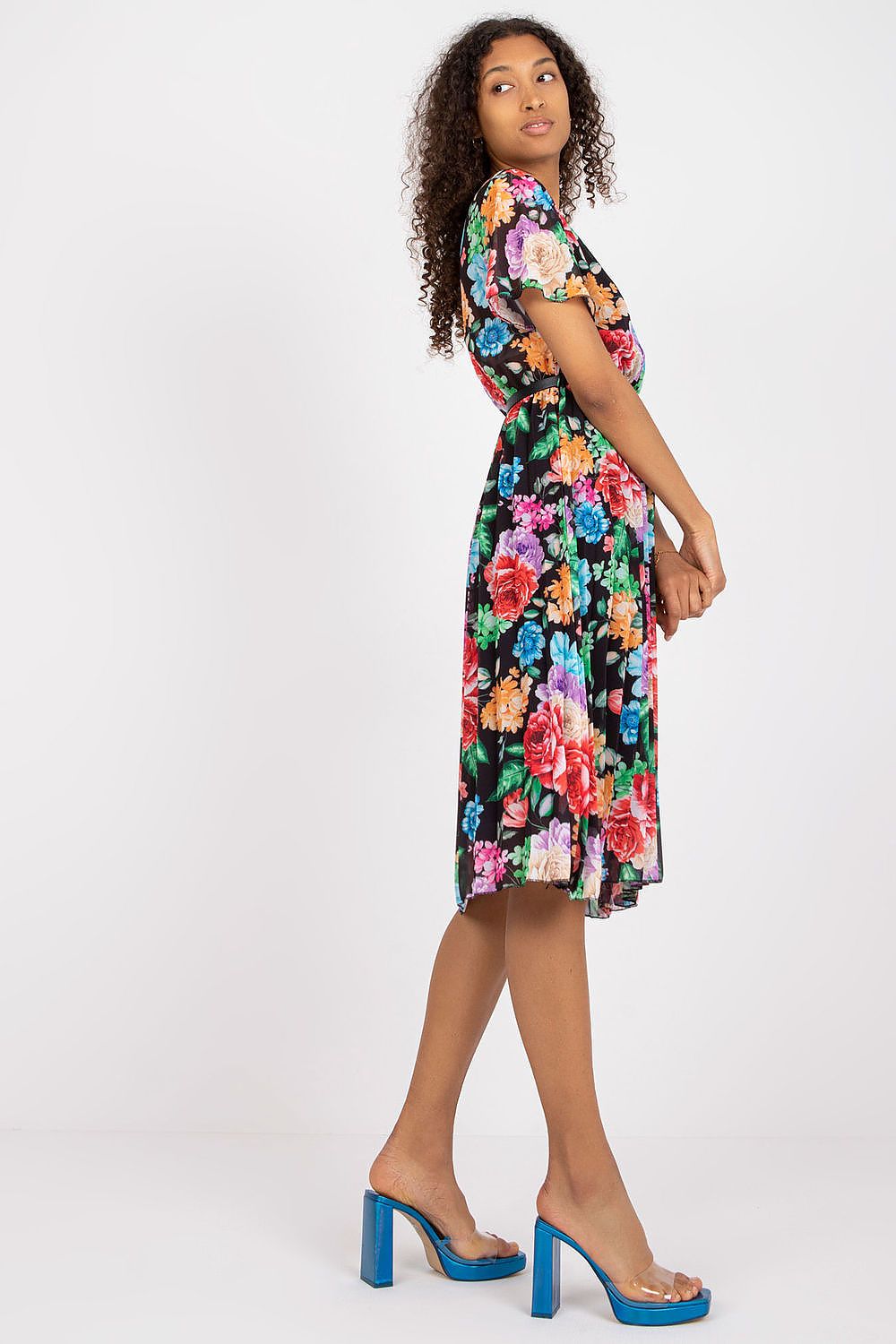 Fashionable floral summer dress with belt and pleated hem by Italy Moda, model captured from the side in a stunning black design with vivid floral accents.