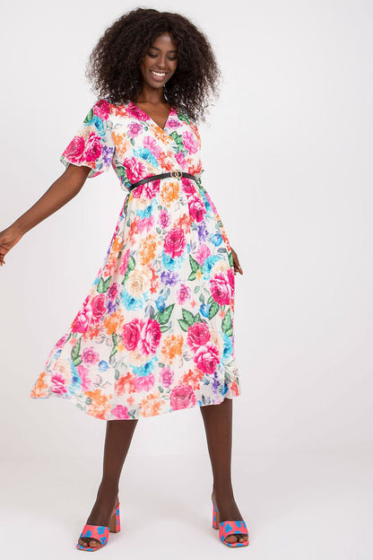 Floral Summer Dress with Belt and Pleated Hem by Italy Moda - Elegant Flared Design. A model showcases the vibrant floral dress with a flared cut, featuring short sleeves, an envelope neckline, and a stylish belt, exuding summer elegance.