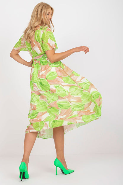 Elegant Summer Dress with Short Frilled Sleeves and Belted Waist by Italy Moda featuring a model twirling in a vibrant green floral print, showcasing the flared bottom and exquisite styling.