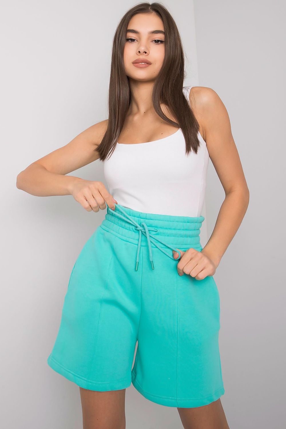Elegant Cotton Women's Shorts with Elastic Waistband and Slip-On Pockets by BFG, model confidently displaying turquoise shorts and white tank top, featuring a cinched elastic waist.