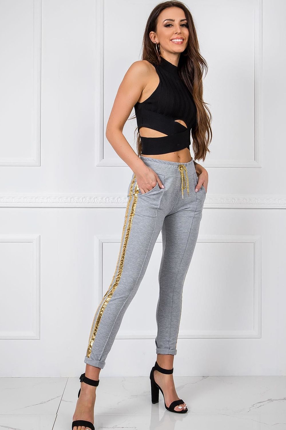 Luxury Women's Tracksuit Trousers with Elastic Waistband and Contrasting Side Stripes, elegant view of model wearing grey tracksuit trousers with eye-catching gold stripes, complemented by a chic black top.