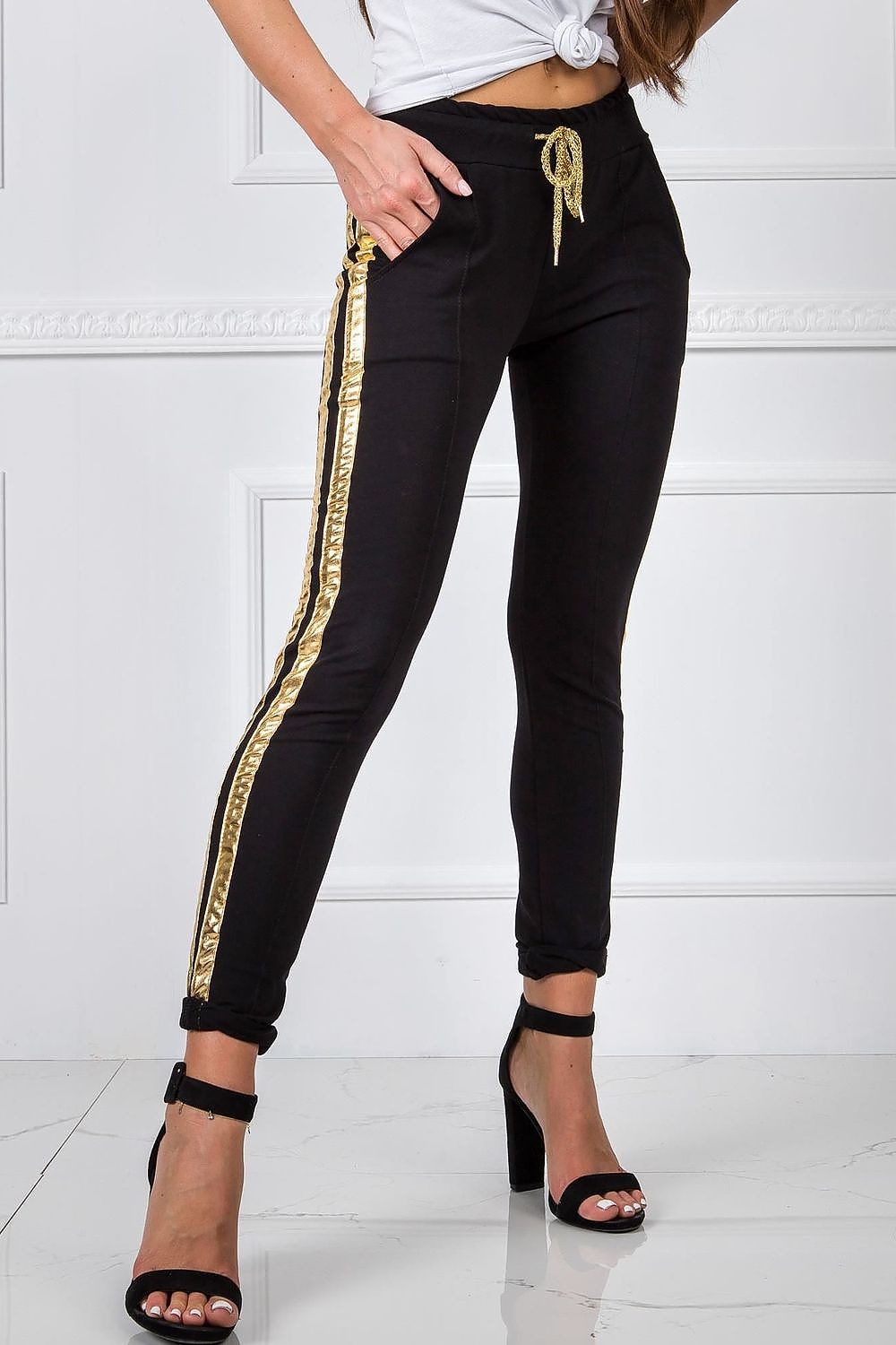 Luxury Women's Tracksuit Trousers with Elastic Waistband and Contrasting Side Stripes, model wearing sleek black tracksuit trousers with striking gold stripes, paired with fashionable high heels.