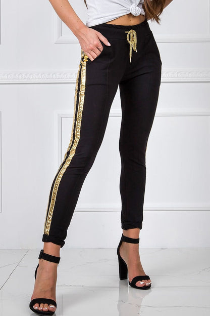 Luxury Women's Tracksuit Trousers with Elastic Waistband and Contrasting Side Stripes, model wearing sleek black tracksuit trousers with striking gold stripes, paired with fashionable high heels.