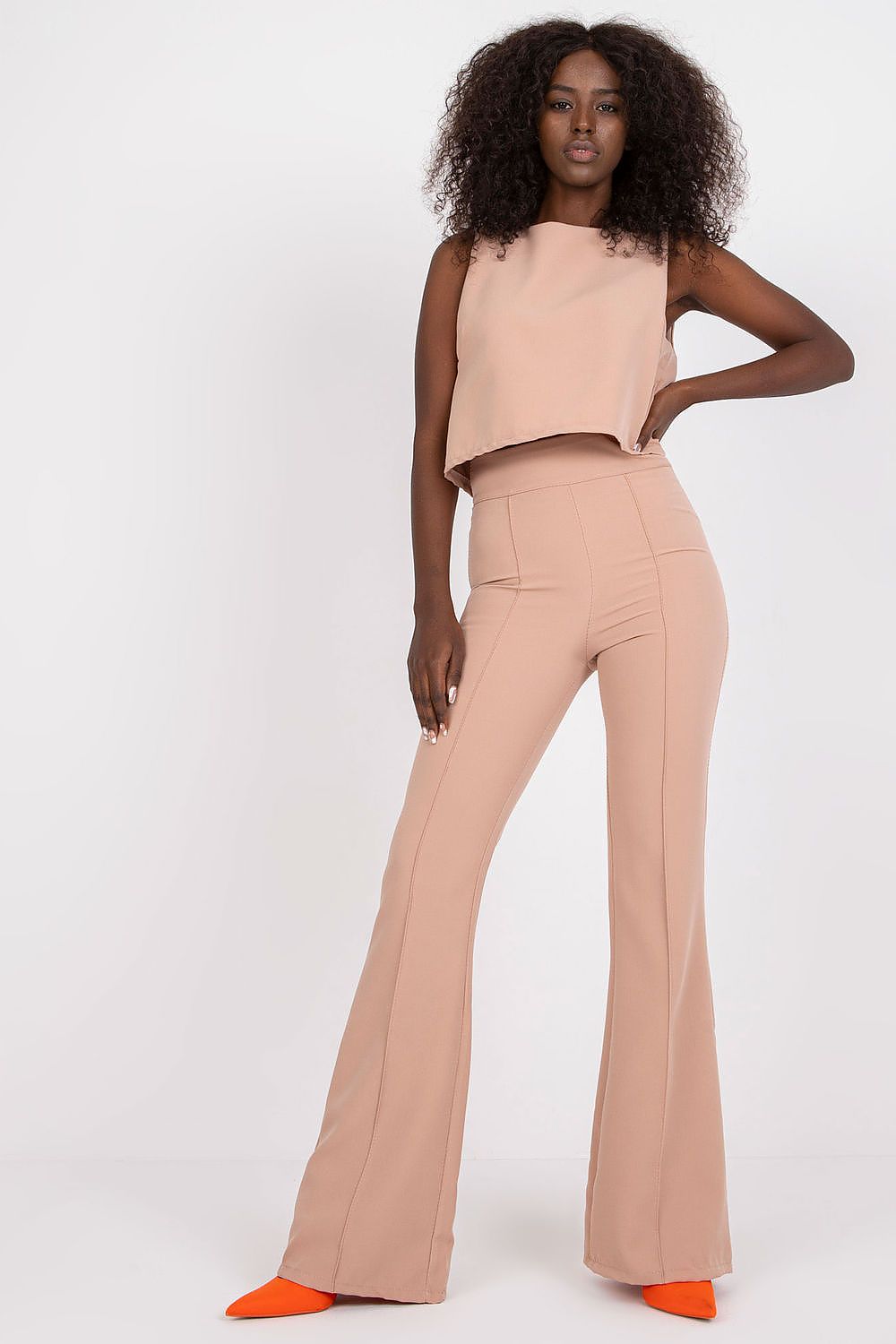 Elegant Italy Moda Blouse and Long Pants Set featuring a sleeveless tie-back design, paired with high waist trousers, model exuding confidence in a chic setting.