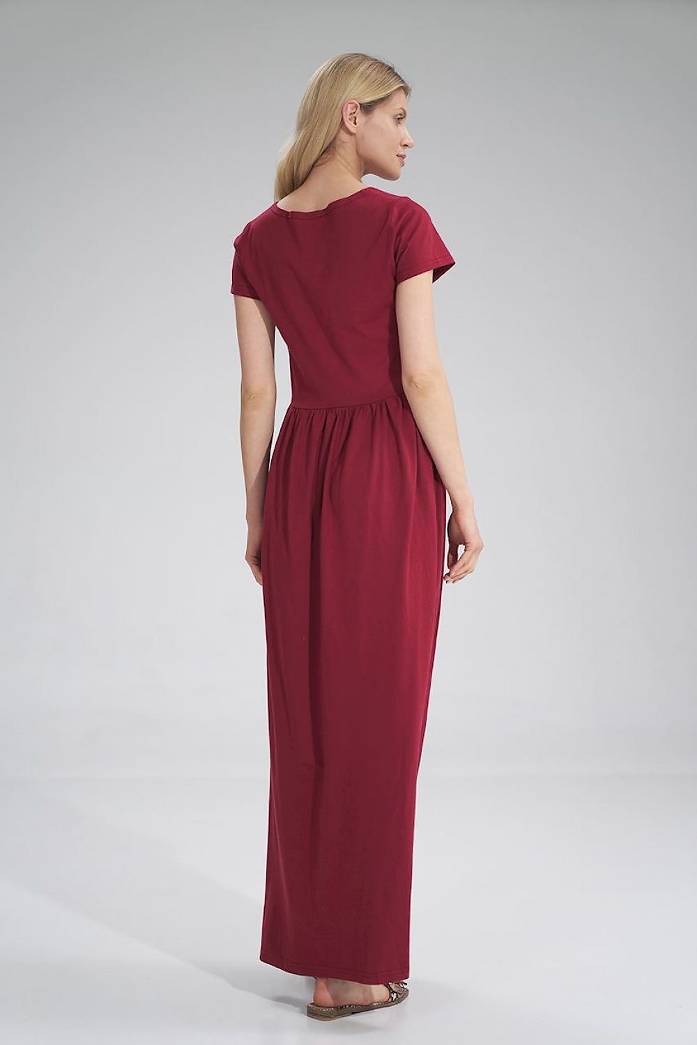 Back view of the Luxury Figl Summer Cotton Maxi Dress showcasing its pleated waist and slit detail, model exuding sophistication in burgundy.