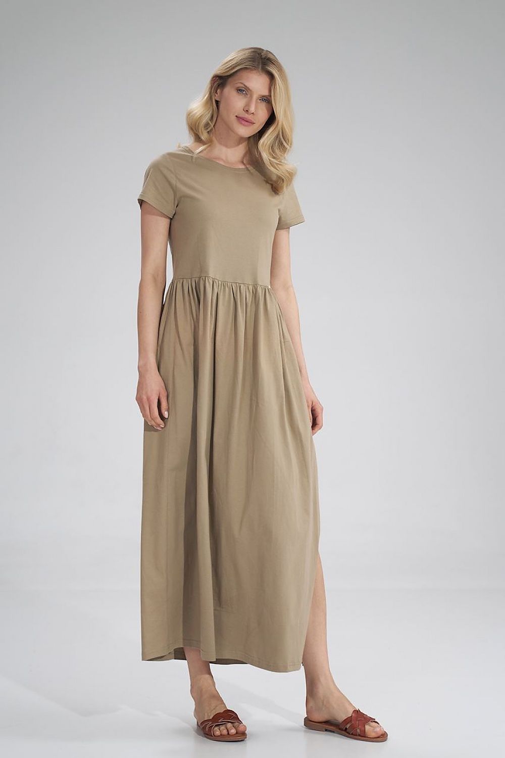 Luxury Figl Summer Cotton Maxi Dress showcased in a neutral tone, model elegantly poses in short-sleeved dress with pleated waist and side slit.