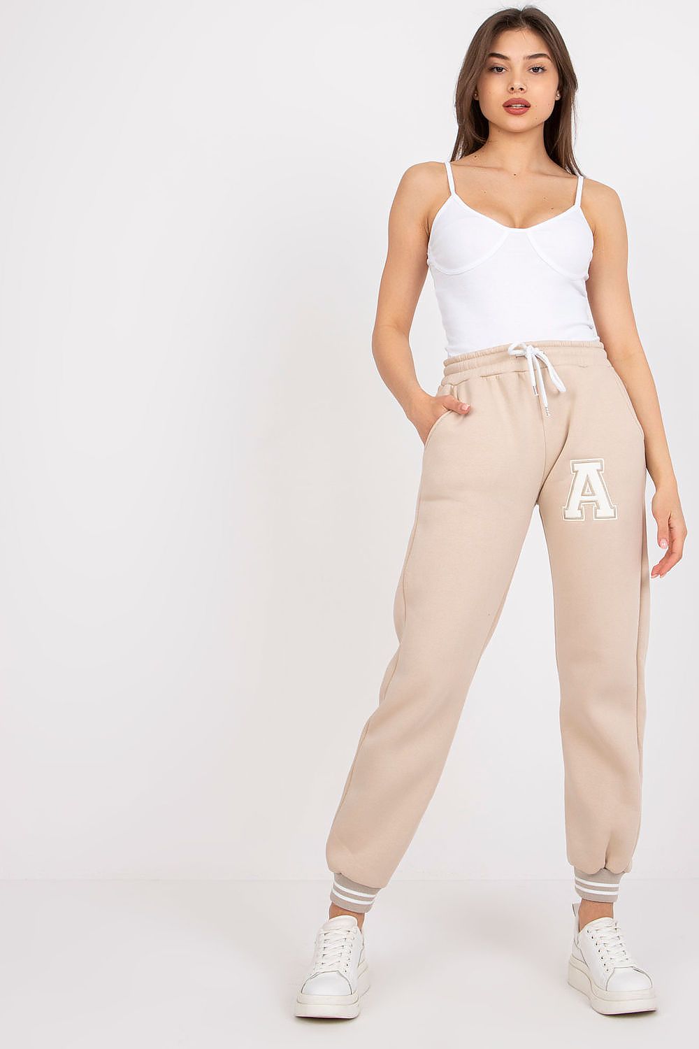 Fashionable model wearing Ex Moda Women's Cotton-Blend Sweatpants with Elastic Waistband and Slip-On Pockets, standing confidently in a light-coloured environment, paired with a simple yet chic white top.
