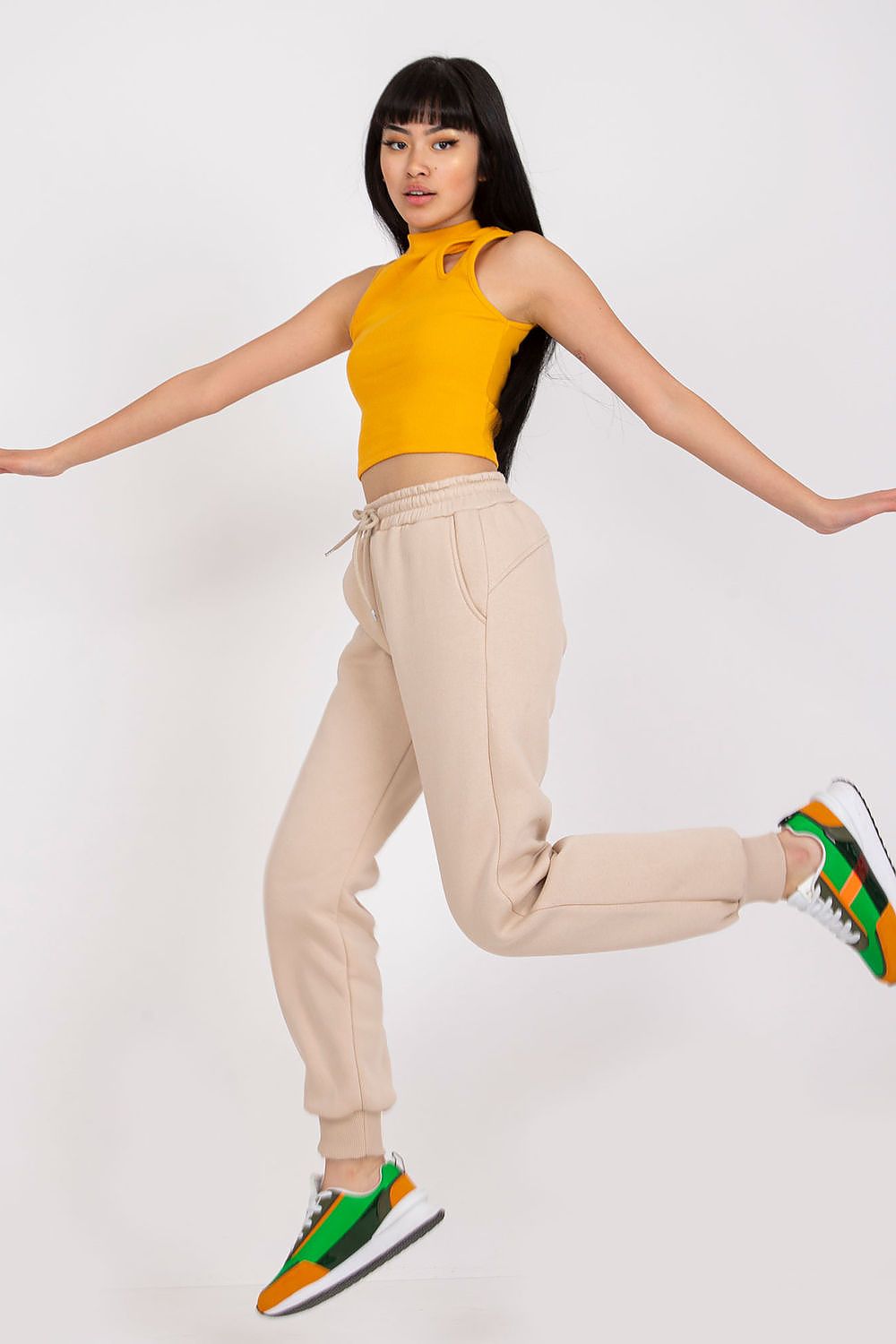Dynamic shot of Ex Moda Women's Tracksuit Trousers in beige, model jumping with grace, featuring a fitted yellow crop top and trendy trainers, showcasing the balance of comfort and fashion.