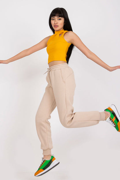 Dynamic shot of Ex Moda Women's Tracksuit Trousers in beige, model jumping with grace, featuring a fitted yellow crop top and trendy trainers, showcasing the balance of comfort and fashion.