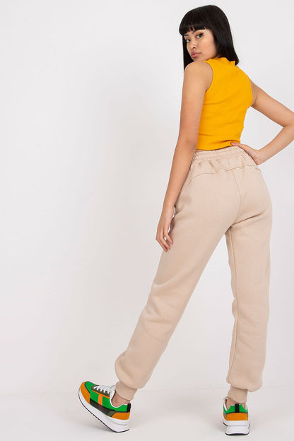 Elegant rear view of a model wearing Ex Moda Women's Tracksuit Trousers in beige, stylishly paired with a chic yellow crop top and trendy footwear, highlighting the modern design.
