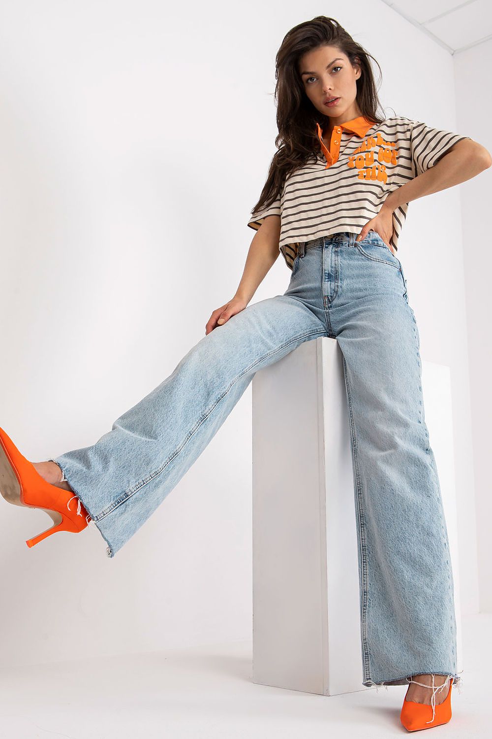 Stylish Striped Cotton Polo Blouse with Decorative Print, featuring a model striking a pose in an elegant striped polo paired with wide-leg jeans and vibrant orange heels, epitomising modern chic.