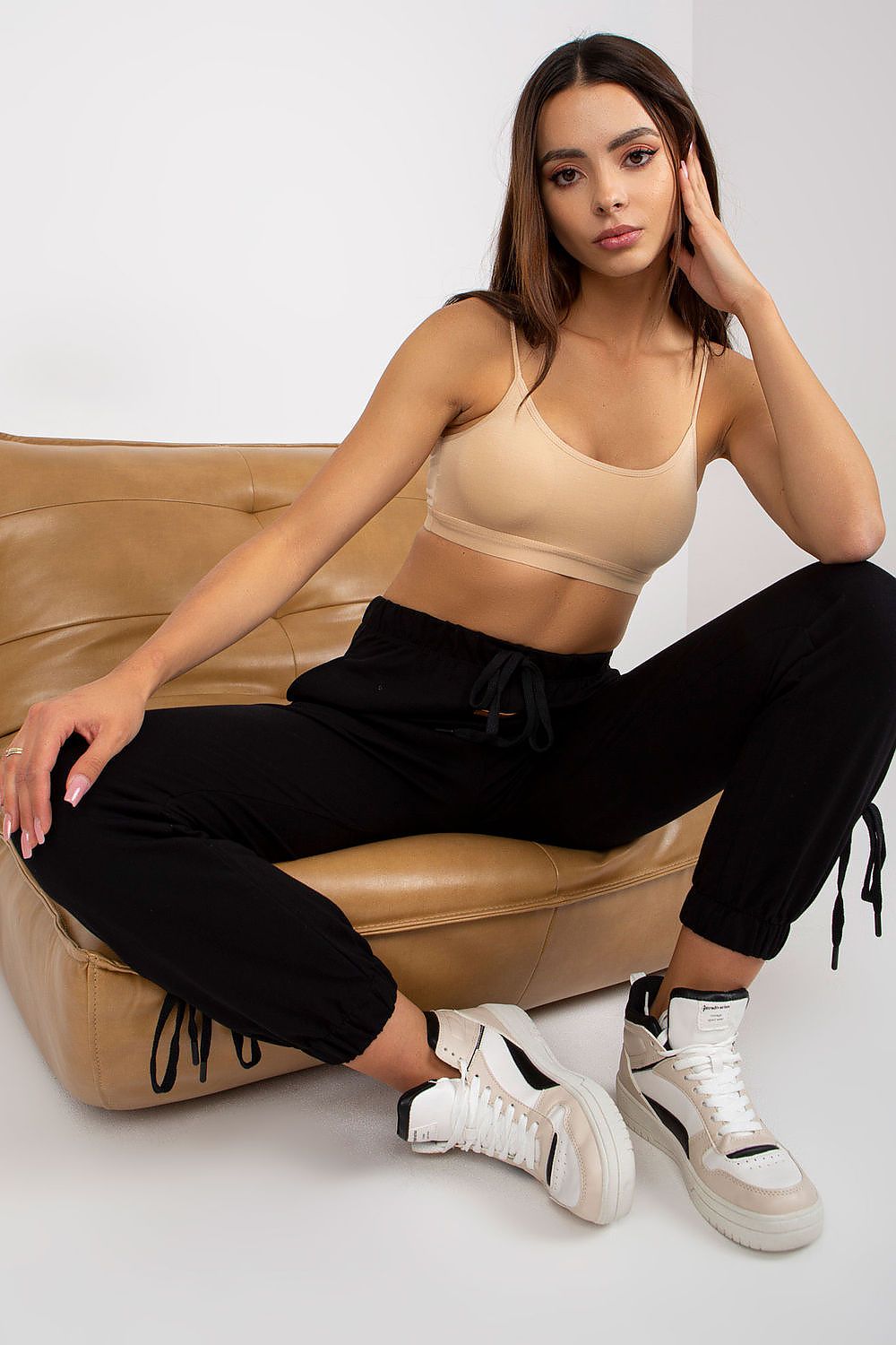 Luxury high rise sweatpants with tie waist and slip-on pockets, showcased in a stylish black outfit, featuring a model seated on a chic sofa, ideal for comfortable fashion.