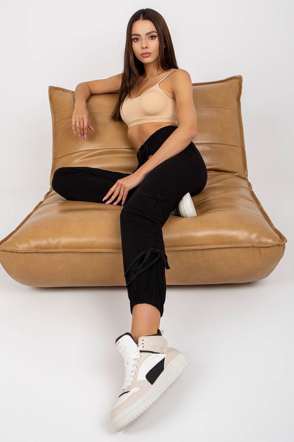 Luxury high rise sweatpants with tie waist and slip-on pockets, elegantly displayed on a model lounging on a designer sofa, with a focus on refined comfort and style.