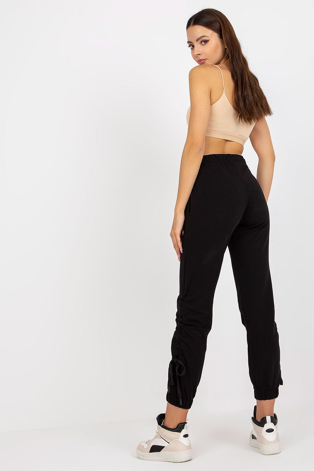 Luxury high rise sweatpants with tie waist and slip-on pockets, captured from the back on a model, presenting a sophisticated look paired with stylish sporty footwear.