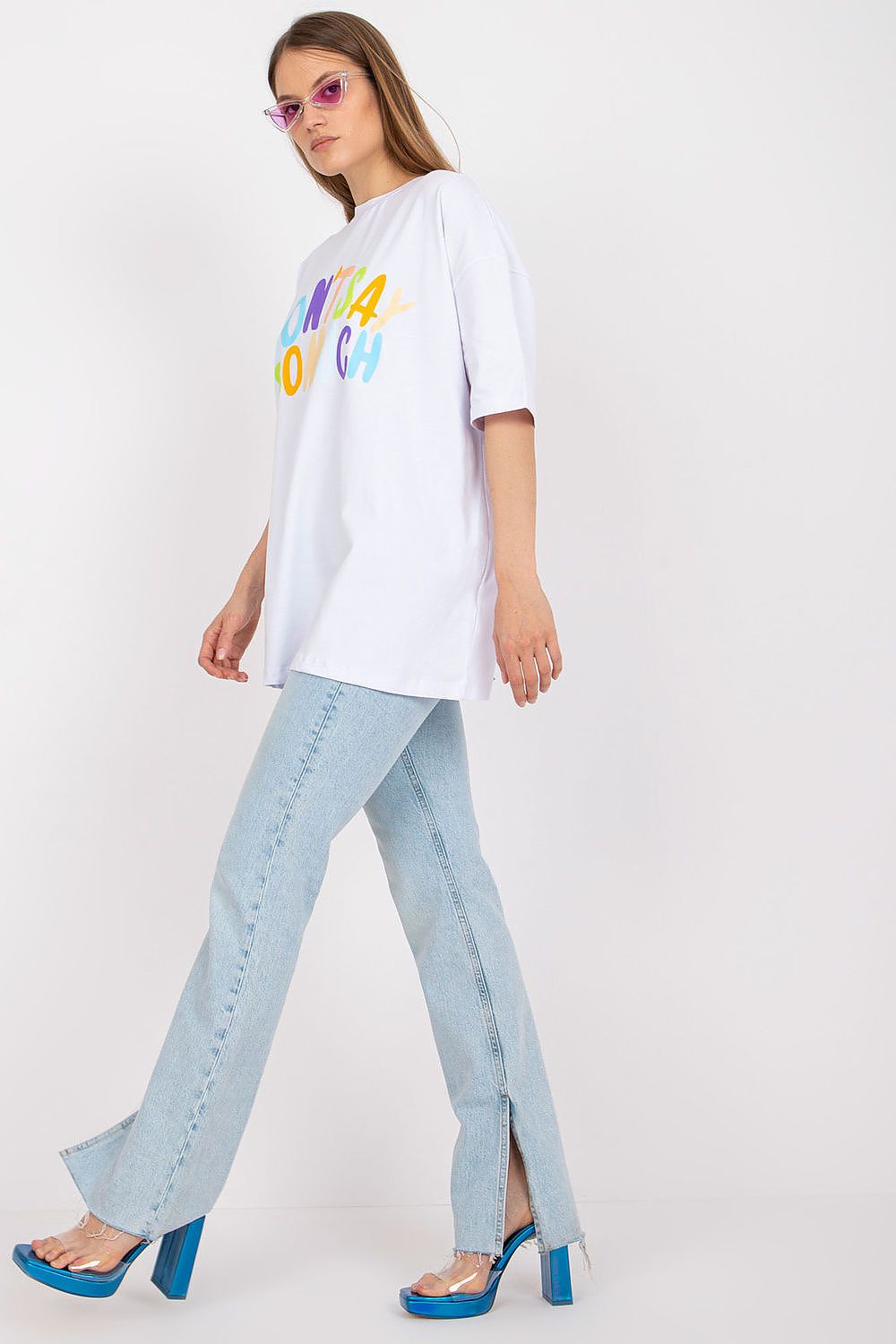 Stylish Loose-Fit Ladies' T-Shirt with Decorative Front Wording - Cotton & Spandex Blend, model showcasing the t-shirt in white with vibrant decorative text, styled with light denim flares and fashionable heels.