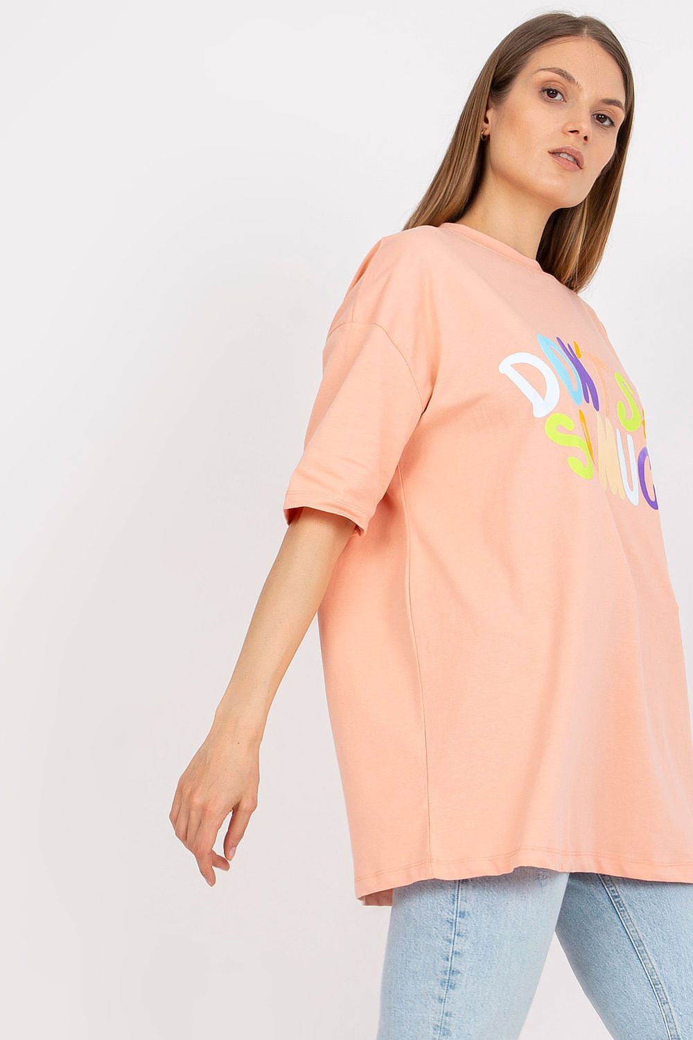 Stylish Loose-Fit Ladies' T-Shirt with Decorative Front Wording - Cotton & Spandex Blend, model presenting an elegant look in a peach t-shirt featuring playful decorative text, paired with trendy jeans.