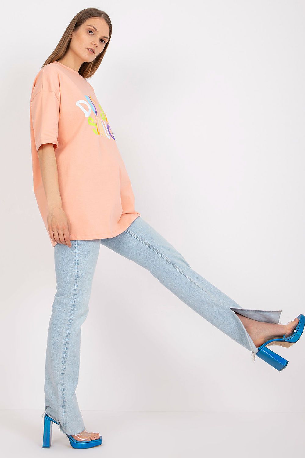 Stylish Loose-Fit Ladies' T-Shirt with Decorative Front Wording - Cotton & Spandex Blend, model displaying a chic look in a peach t-shirt adorned with colourful text, complemented by stylish flared jeans.
