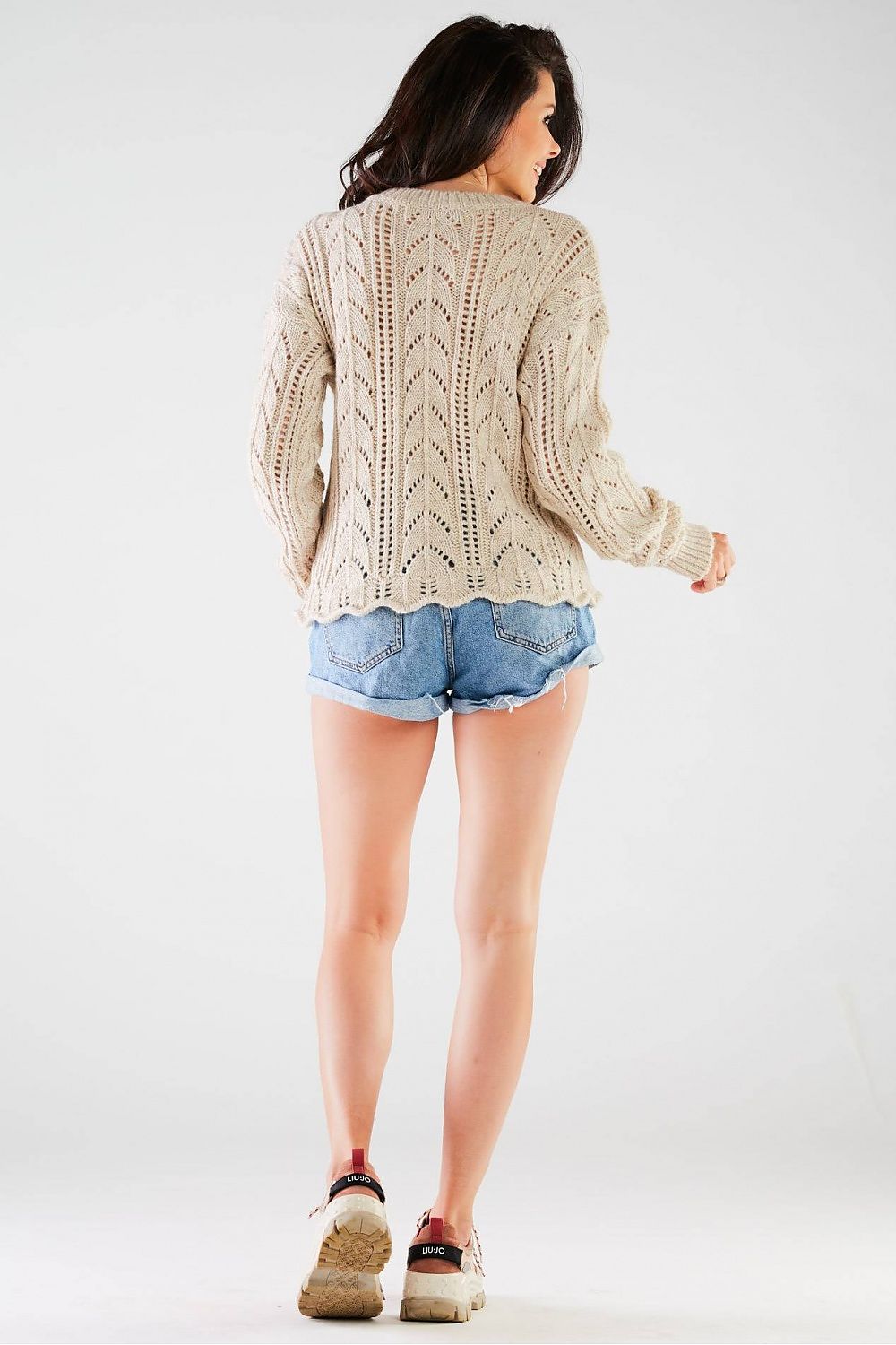 Back view of the Luxury Ladies Sweater by Awama, demonstrating the timeless ribbed finish and airy knit design, paired with stylish denim shorts.