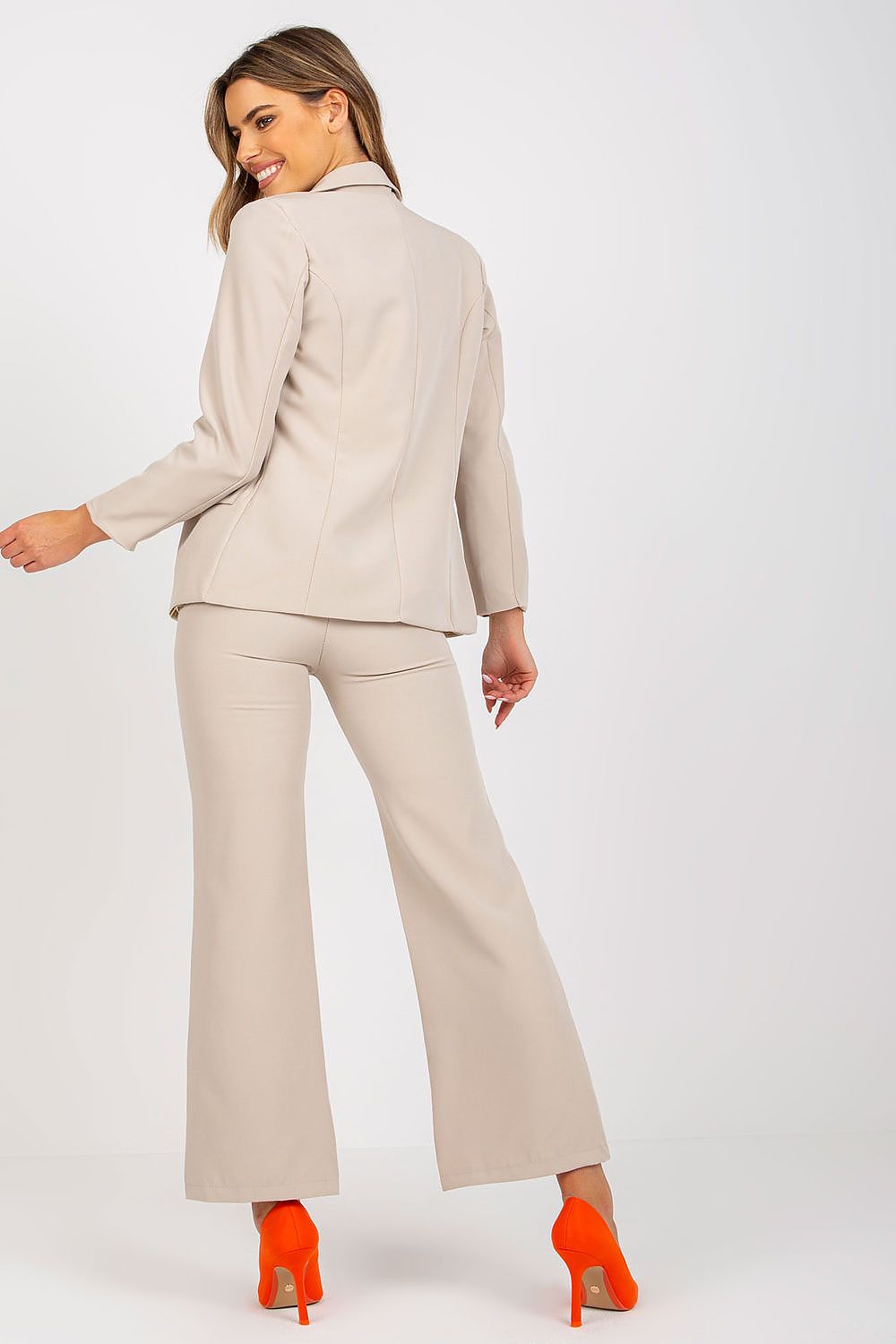 Back view of the Stylish Ladies' Jacket by Italy Moda, highlighting the tailored fit and structured design, elegantly paired with trousers and striking orange high heels.