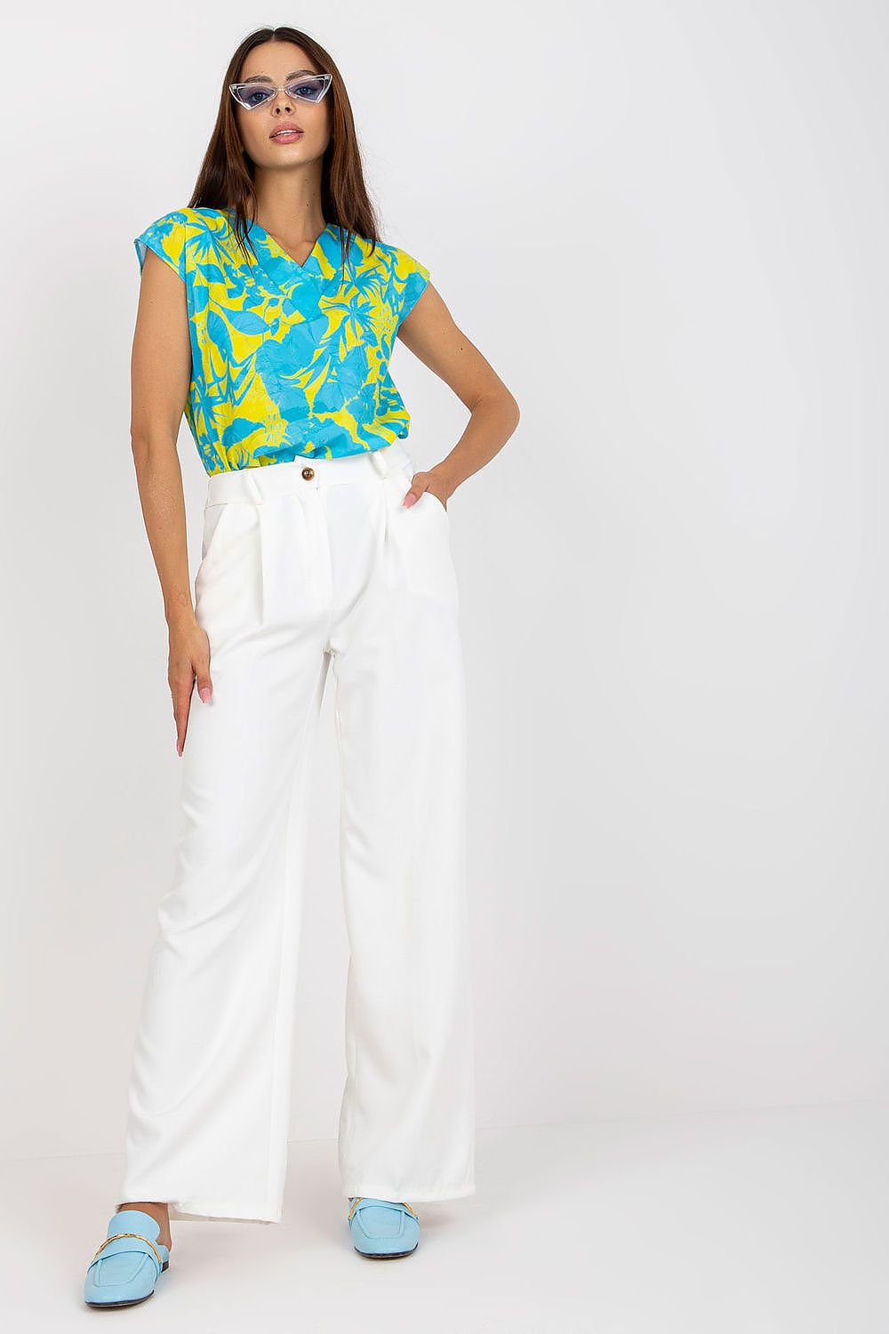 Luxury Women’s Italy Moda Trousers showcased on a model wearing high-rise fabric pants with zip and button fastening, paired with a vibrant blue and yellow floral top, exuding elegance and sophistication.