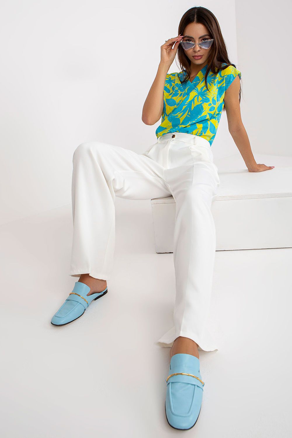 Luxury Women’s Italy Moda Trousers - High Rise Fabric Pants with Zip and Button Fastening, displayed stylishly with a vibrant blue and yellow patterned top and blue loafers, showcasing a chic summer outfit.