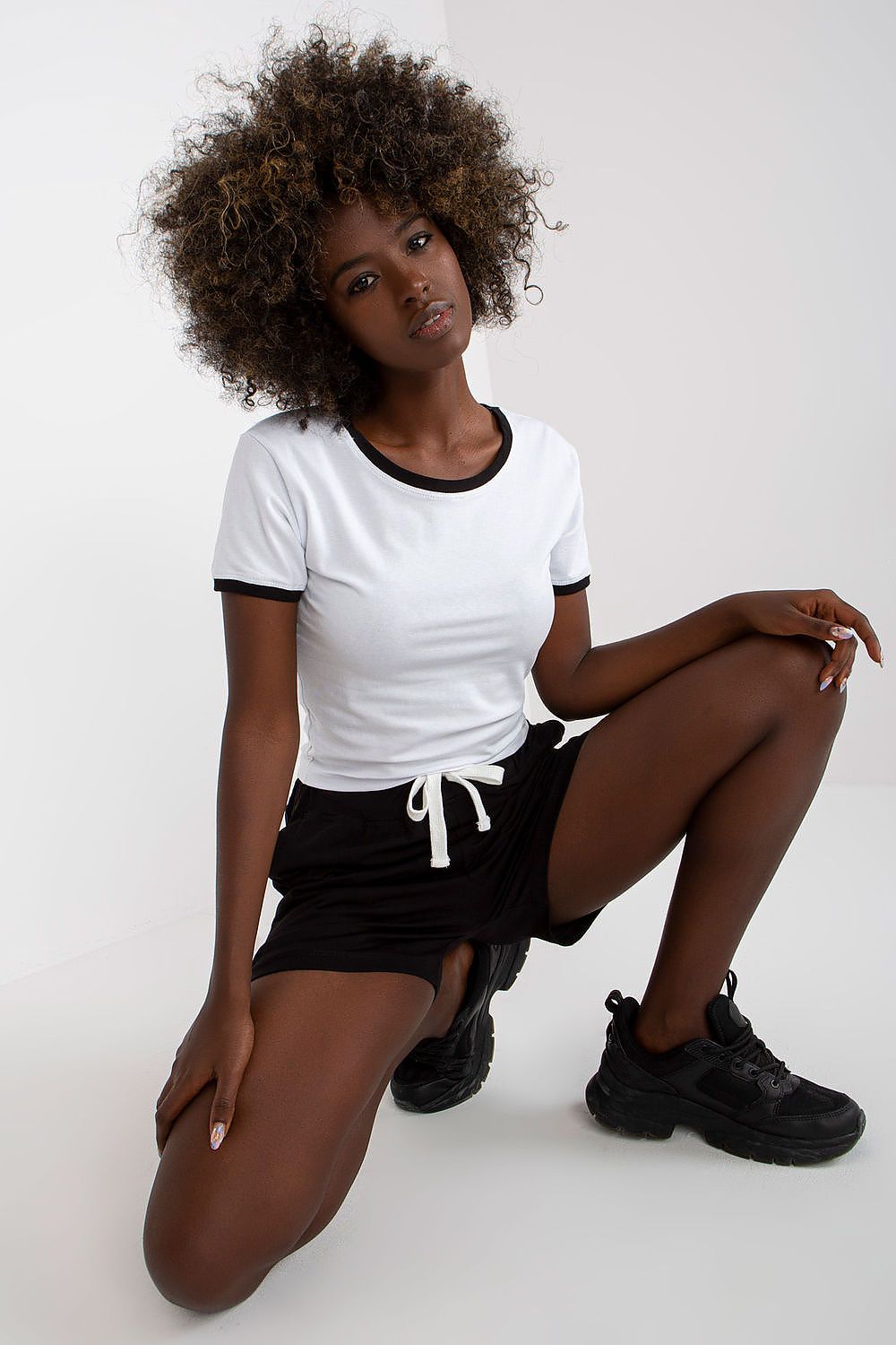 Ex Moda Ladies 2-Piece Cotton T-Shirt and High Waisted Shorts Set with Pockets, featuring a stylish model presenting a chic white t-shirt with black trim paired with high-waisted black shorts, exuding modern elegance.