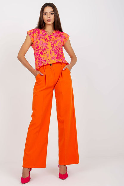 Luxury Women’s Italy Moda Trousers - High Rise Fabric Pants with Zip and Button Fastening, showcased by a model wearing bright orange trousers and a vibrant pink floral top.