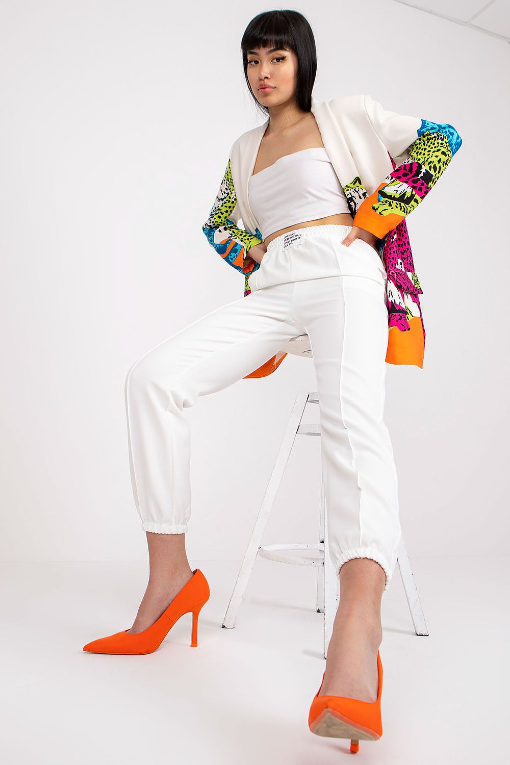 Trendy women's luxury high-rise trousers with elastic waist and pockets by Italy Moda, featured in a crisp white colour, worn with a colourful patterned jacket and orange heels for a bold statement.