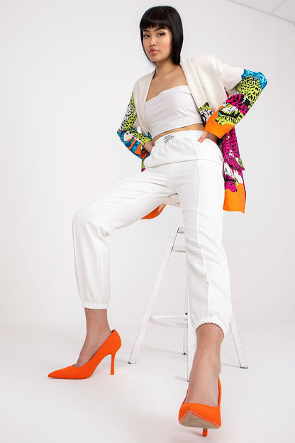 Trendy women's luxury high-rise trousers with elastic waist and pockets by Italy Moda, featured in a crisp white colour, worn with a colourful patterned jacket and orange heels for a bold statement.