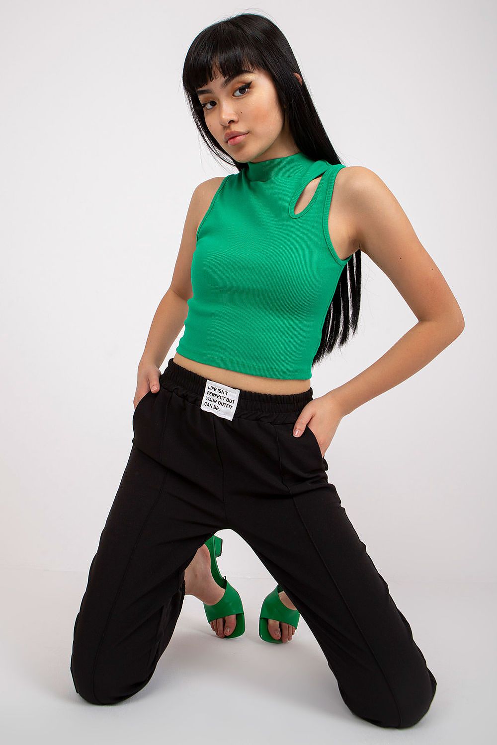 Confident woman posing in Women’s Luxury High-Rise Trousers with Elastic Waist and Pockets by Italy Moda, featuring a green top and stylish black trousers.