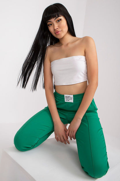 Chic green trousers for women by Italy Moda with high-rise fit, elastic waist, and pockets, elegantly worn with a simple white crop top.