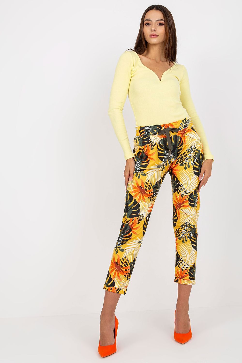 Sophisticated look featuring Women's Relevance Tracksuit Trousers in a lively floral print, matched with a luxurious yellow top and high orange heels, radiating summer vibes.