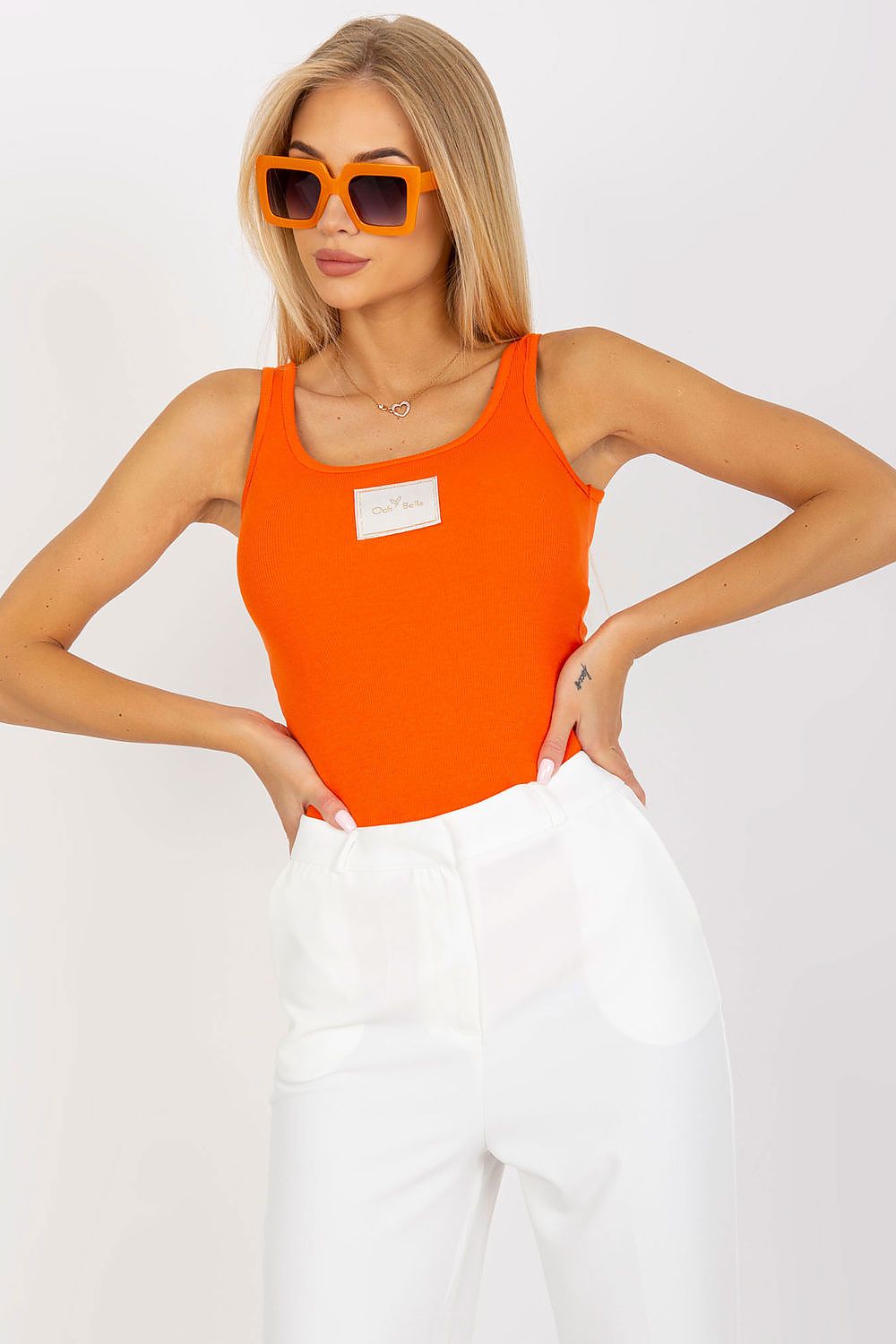 Stylish Och Bella Elegant Ribbed Cotton Spandex T-Shirt with Decorative Patch, featured in vibrant orange, paired with chic white trousers, perfect for a luxurious summer look.