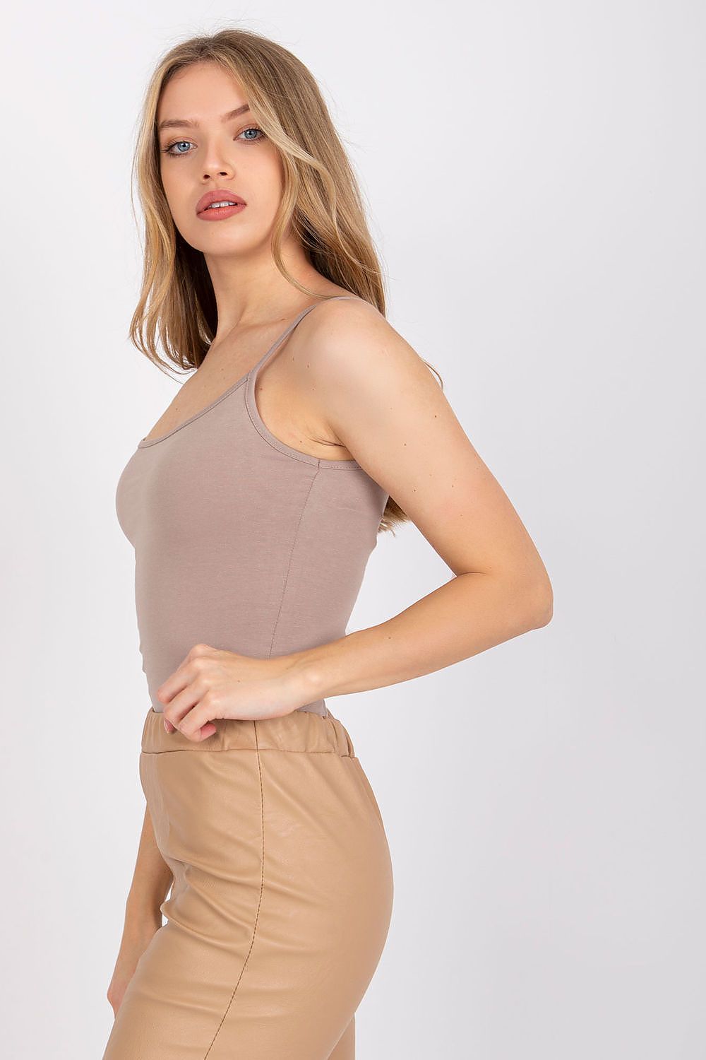 Side view of a model flaunting a luxurious cotton spandex strapless shirt with round neckline in taupe, accentuated by beige leather pants - perfect for versatile styles.