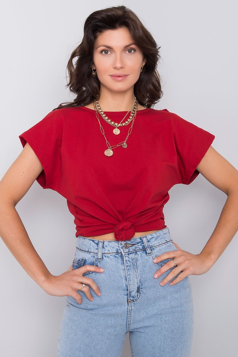 Chic red variation of the elegant short sleeve blouse with frill trimmed deep cut-out, model styled with gold accessories, showcasing the trendy knot front detail.