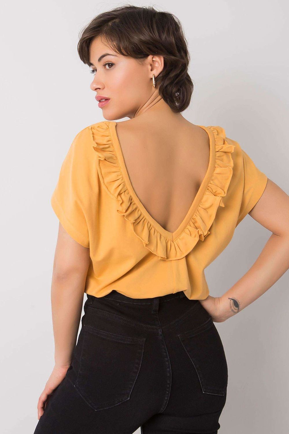 Chic back view of the Elegant Short Sleeve Blouse With Frill Trimmed Deep Cut-Out in mustard yellow, featuring an exquisite frill detail on the neckline, worn by a stylish woman.