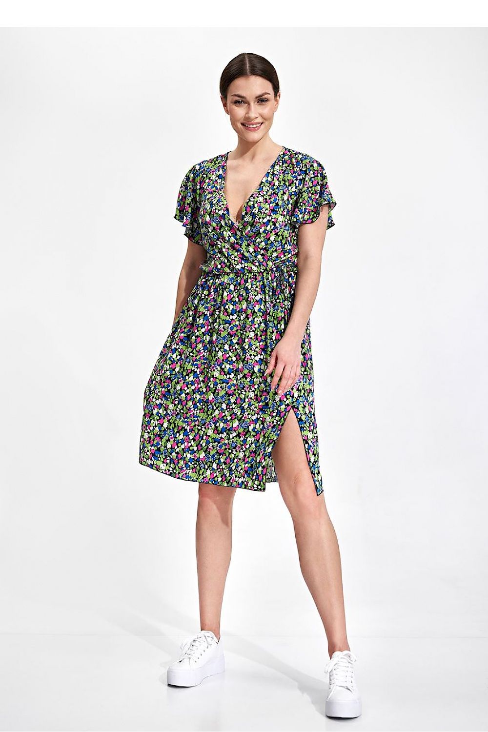 Summer Midi Dress by Figl in a charming floral design, displaying an envelope neckline and ethereal sleeves. The model presents this luxurious piece styled with contemporary white sneakers for a chic look.