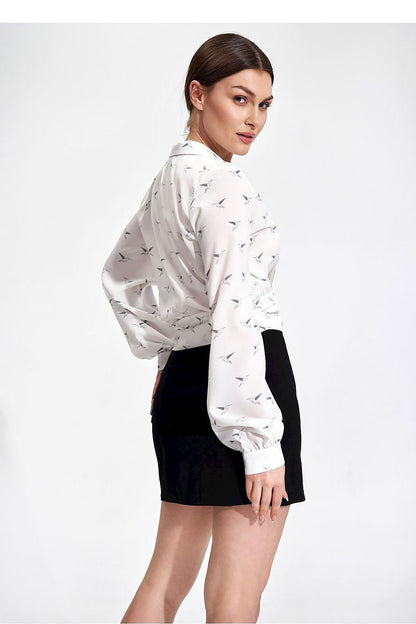 Luxury Figl Unlined Mini Skirt with Side Zip and Front Slit, model wearing a chic bird-print blouse with a black mini skirt, exuding confidence and luxury fashion.