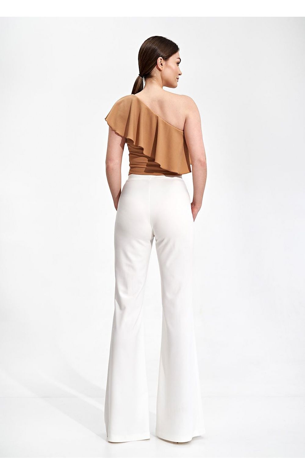 Back view of the Elegant One Shoulder Ruffle Crop Top Blouse by Figl, featuring ruffle detail, styled with elegant white trousers.