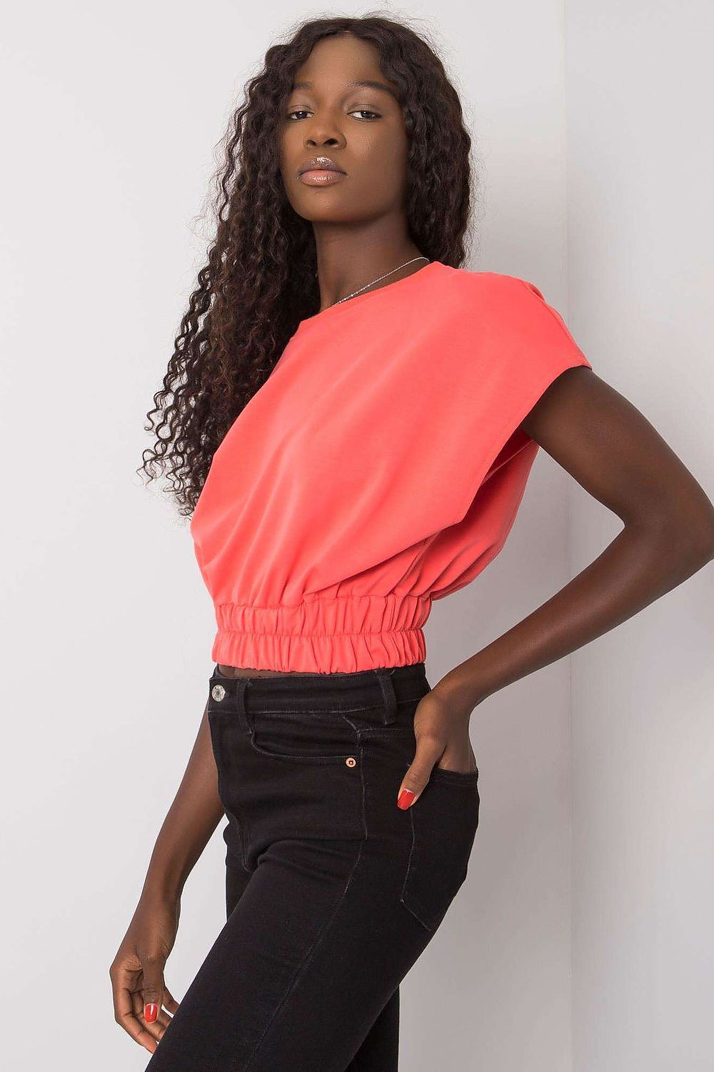 Luxury Ladies' Loose Fit Sweatshirt with Short Sleeves and Wide Rubber Band in vibrant coral, elegantly worn with black trousers, embodying chic and comfortable styling.