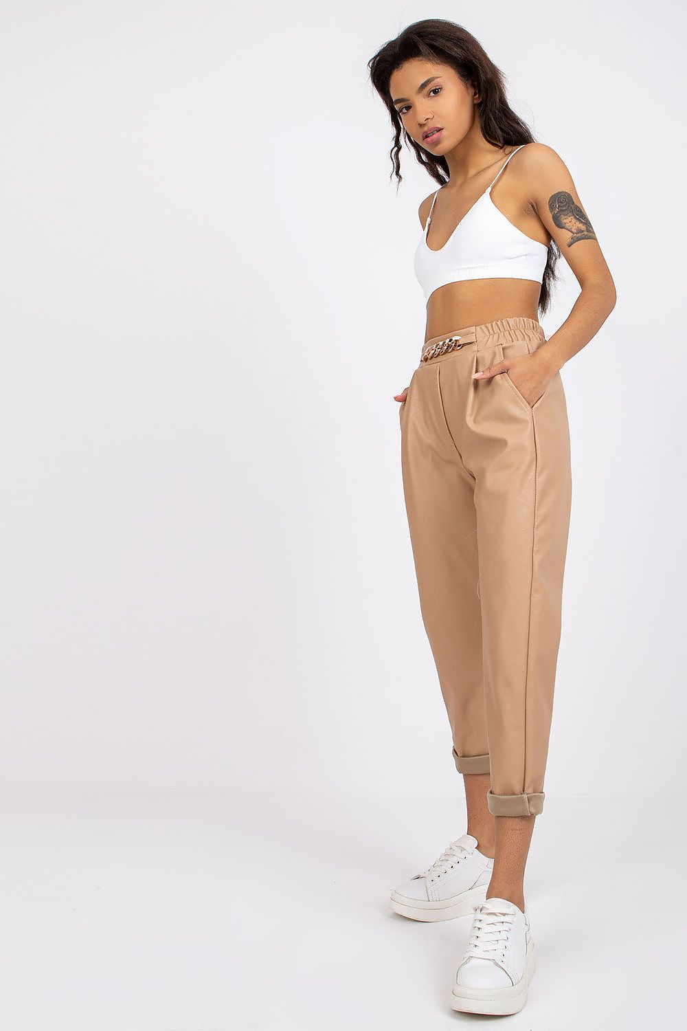Luxury Women's 7/8 Eco Leather Trousers with High Rise and Decorative Chain by Italy Moda, model in elegant white bralette and beige trousers featuring decorative chain detail.