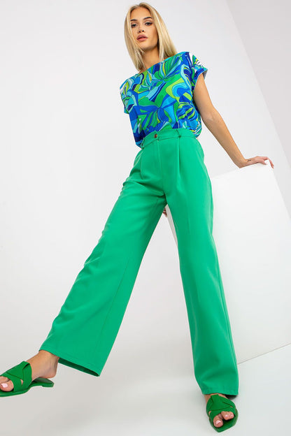 Luxury Women’s Italy Moda Trousers - High Rise Fabric Pants with Zip and Button Fastening, portrayed by a model stylishly demonstrating green trousers with a vibrant blue and green patterned top.