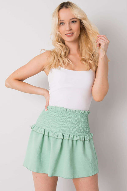 Och Bella Women's Short Summer Skirt with Wide Elastic Waistband in green, paired with a white tank top for a fresh, elegant summer outfit.