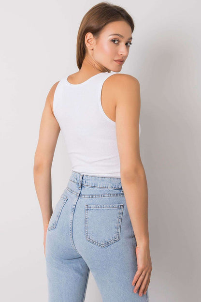 A stylish woman showcasing the Och Bella Sleeveless T-Shirt with Heart Neckline and Decorative Pocket, made of 95% cotton, paired with high-waisted light blue jeans, presented in an elegant setting.