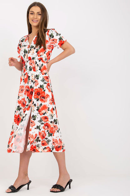 Elegant Floral Summer Dress with Short Sleeves, Front Buttons and Frill by Italy Moda, showing a model joyfully standing in a beautiful floral dress with a thigh-high slit, completed with sleek black heels.