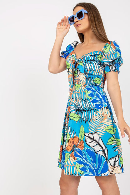 Elegant Summer Dress by Italy Moda with Spanish Style Neckline and Decorative Pleats, model elegantly posing with sunglasses, accentuating the bold floral prints and luxurious summer feel.